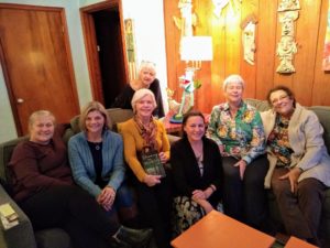 6 middle aged women seated on sofas at night