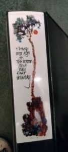 bookmark with stylized tree, orange moon, text: I keep my eyes on the moon and my feet muddy
